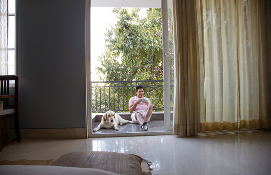 Man drinking coffee and spending some quality time with his dog in the balcony. 