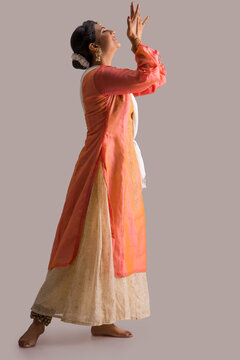 Beautiful kathak dancer performing gracefully over a plain background. 
