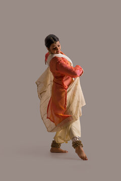 Beautiful kathak dancer performing gracefully over a plain background. 