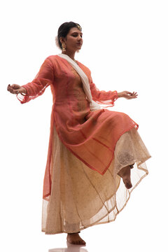 Graceful Kathak dancer standing on one foot during a mesmerising performance in front of a white background. 