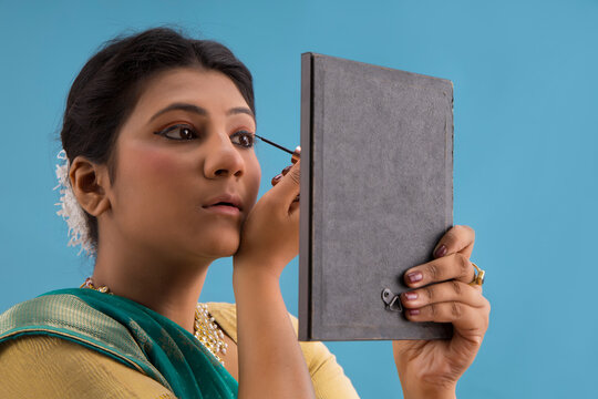 Kathak dancer applying eyeliner on her eyes. 