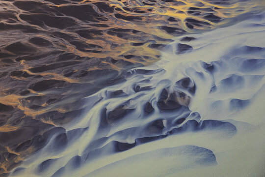 Aerial view of the intricate braided river patterns of the glacial river near Selfoss, with dark volcanic sediment and bright glacial silt in Selfoss, Sveitarfelagid Arborg, Iceland.