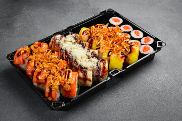 Assorted Japanese sushi rolls topped with fresh salmon shrimp unagi sauce and sesame seeds in takeaway tray. Gourmet seafood set. Tasty fresh Asian food. © Yaruniv-Studio
