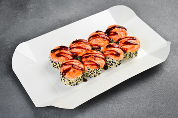 Delicious baked sushi roll set topped with creamy cheese and unagi sauce in takeaway box. Fresh Japanese rolls wrapped in nori. Tasty gourmet food. © Yaruniv-Studio