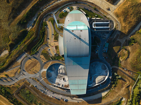 Aerial view of the Energy Recovery Facility with its distinctive oval roof, surrounding access roads, and industrial infrastructure in Bicester, England, United Kingdom.