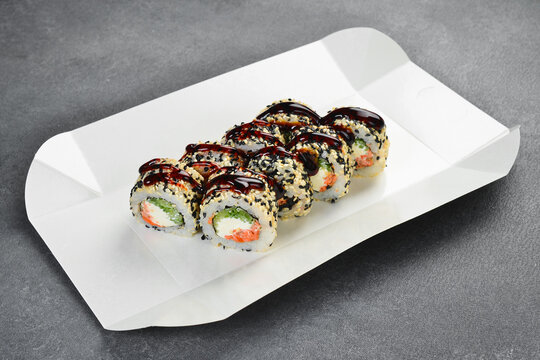 Unagi roll set inside open white delivery paper box. Delicious sushi with eel, cream cheese, cucumber, sesame seeds, unagi sauce. Fresh Japanese seafood takeaway food concept.