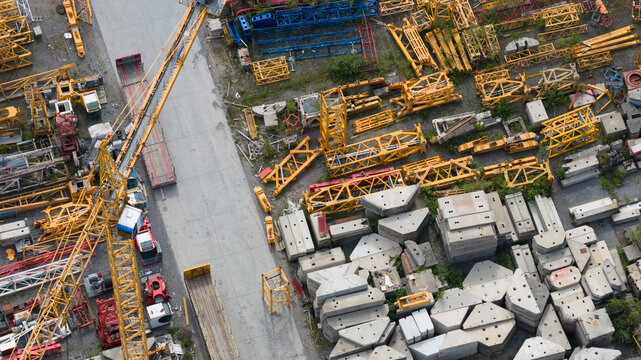 Aerial view of Feluy de Parc Industriel showing yellow crane components, steel lattice structures, and stacked concrete blocks in a storage yard in Seneffe, Region wallonne, Belgium.