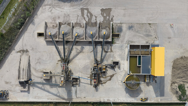 Aerial view of a gravel and sand processing plant with conveyor belts, aggregate piles, and water treatment tanks in La Longueville, Hauts-de-France, France.