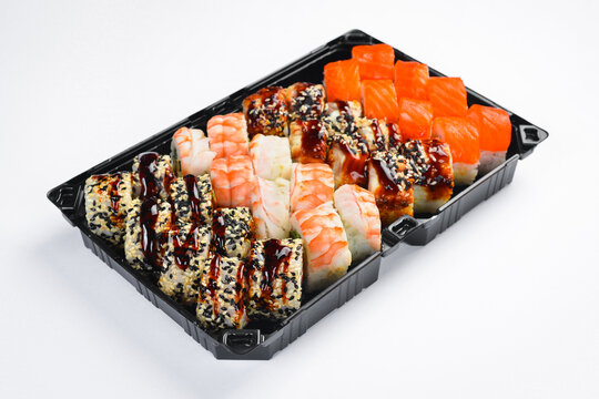 Large Japanese sushi roll set with salmon shrimp and unagi eel isolated on white background. Assorted rolls served in black takeaway tray. Fresh seafood.