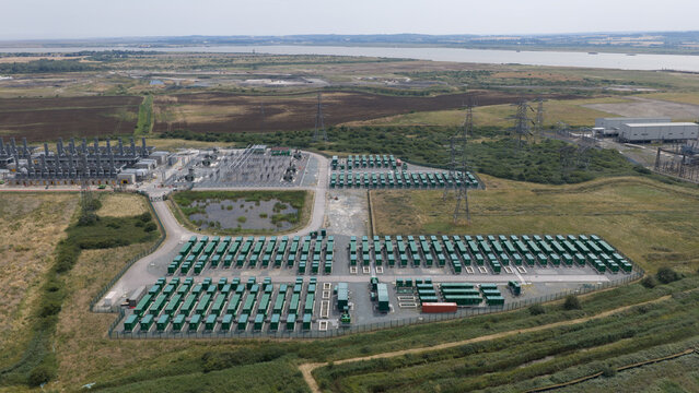 Aerial view of Thurrock Flexible Generation Substation with rows of green battery storage containers and electrical infrastructure in a rural landscape in Tilbury, England, United Kingdom.