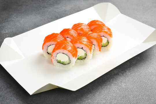 Fresh Philadelphia sushi rolls with salmon, cream cheese, and cucumber are served on paper tray. Enjoy this traditional Japanese seafood dish today. Order now.