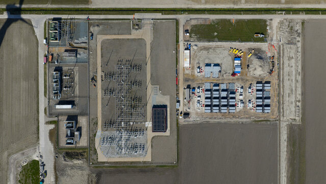 Aerial view of Hoogspanningsstation - Westermeerdijk featuring the electrical substation with transformers, switchyard, and battery storage containers in Espel, Flevoland, Netherlands.