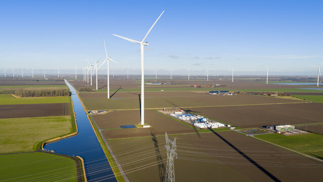 Aerial view of wind turbines in a field with a canal and power lines in Dronten, Flevoland, Netherlands.