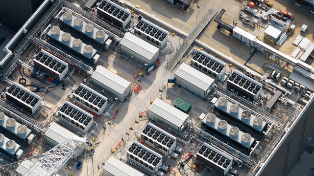 Aerial view of industrial cooling units and HVAC systems installed on the rooftop of a large data center facility in Slough, England, United Kingdom.