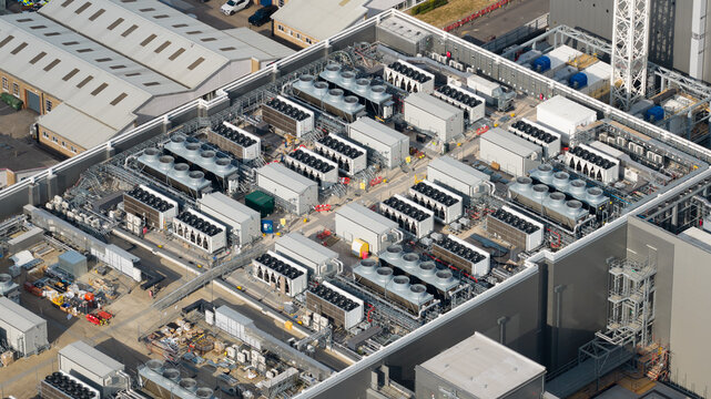 Aerial view of a large data center rooftop featuring rows of industrial cooling units and ventilation fans in Slough, England, United Kingdom.
