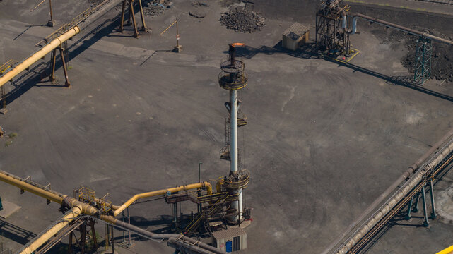 Aerial view of the Cokerie Arcelormittal industrial facility with a prominent flare stack and complex piping systems in Grande-Synthe, Hauts-de-France, France.