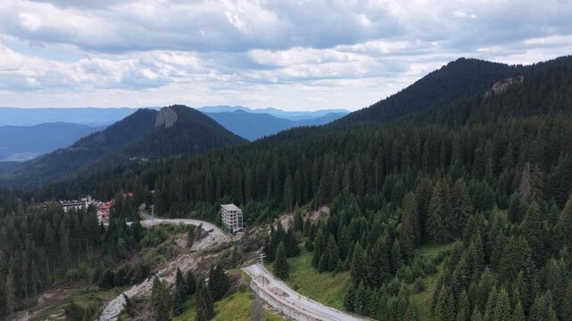 Aerial reveal shot of massive landslide damaging road and building in mountain forest