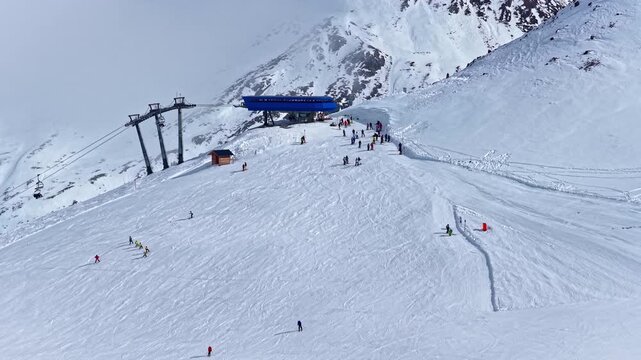 Aerial view of skiers on a snowy slope at the Nauders ski resort with a ski lift station in the background in Nauders, Tyrol, Austria.