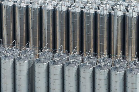 Aerial view of storage facilities for petrochemical products featuring rows of tall stainless steel tanks with industrial piping and ventilation systems in Poland.