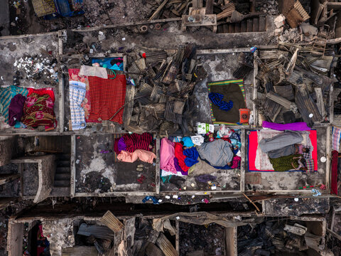 Aerial view of fire aftermath in Korail Basti, showing charred structures, debris, and people resting on colorful blankets amidst the ruins in Dhaka, Dhaka Division, Bangladesh.