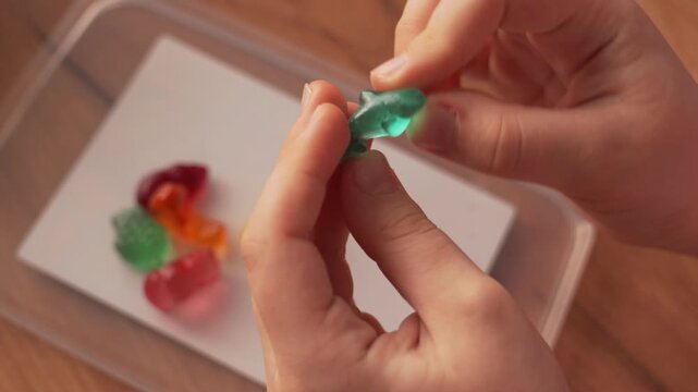 A child is holding a gelatin candy in the shape of a dolphin. The child is demonstrating the sweetness. Gelatin sweet animals.