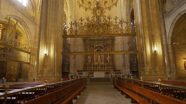 Ornate iron screen and wooden pews within the grand interior of Segovia Cathedral