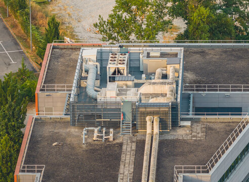 Aerial view of a modern building rooftop featuring industrial HVAC units, ventilation ducts, and technical equipment set against a flat roof surface in Alixan, Auvergne-Rhone-Alpes, France.
