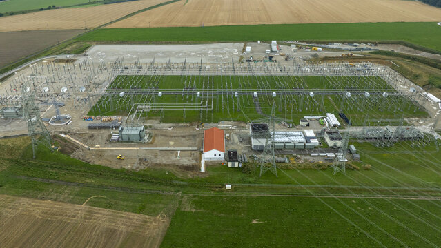Aerial view of Umspannwerk Ottenhofen electrical substation with high-voltage power lines and infrastructure surrounded by agricultural fields in Ottenhofen, Bayern, Germany.