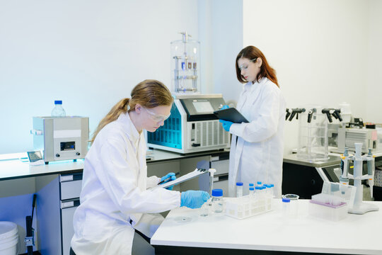Team of scientists analyzing blue liquid samples in a modern lab, showcasing biotechnology, chemistry, and medical research innovation.
