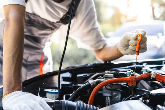 Auto technician performing routine maintenance check on a hybrid car engine.