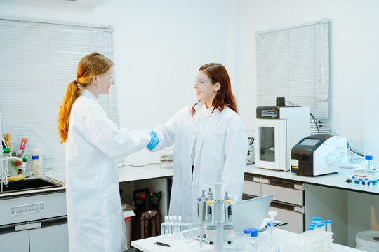 Scientists shaking hands in a modern laboratory after successful biotechnology research, symbolizing teamwork, healthcare innovation and scientific partnership.