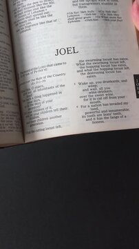 Kuala Lumpur, Malaysia - July 22nd, 2026: Opening to the Book of Joel of the Old Testament in the Holy Bible. New Revised Standard Version. Vertical video.