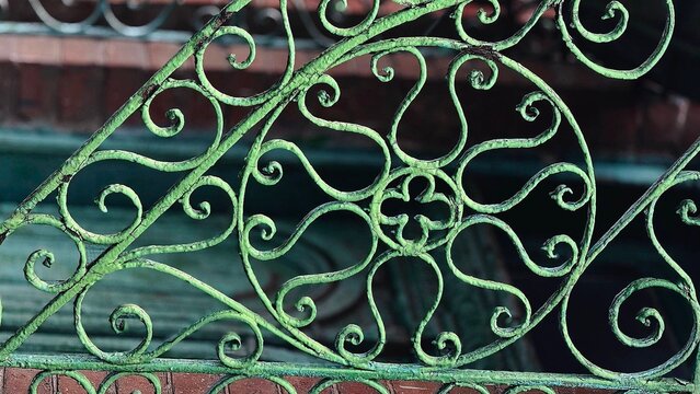 Ornate weathered green iron gate with a highly textured surface featuring peeling paint, rust pitting, oxidation, and layers of aged metal.