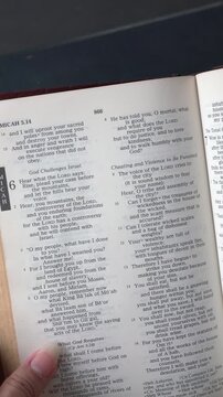 Kuala Lumpur, Malaysia - July 22nd, 2026: Opening to the Book of Micah chapter 6 verse 8 of the Old Testament in the Holy Bible. New Revised Standard Version. Vertical video."