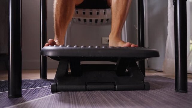 Bare Feet Rest on an Adjustable Footrest beneath a Table, Supporting a Comfortable Seated Position and Ergonomic Wellbeing