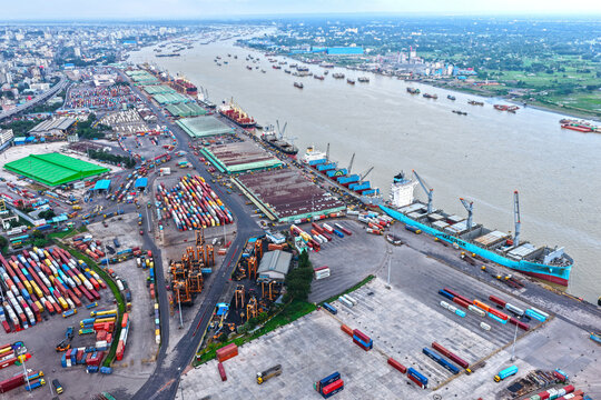 Aerial view of Chattogram Port with cargo ships docked at the quay, rows of colorful shipping containers, industrial cranes, and the Karnaphuli River in Chittagong, Chittagong Division, Bangladesh.