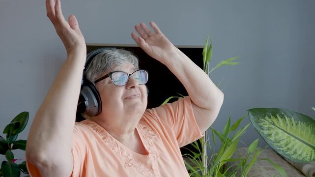 Joyful Senior Woman Dancing With Raised Hands and Headphones at Home