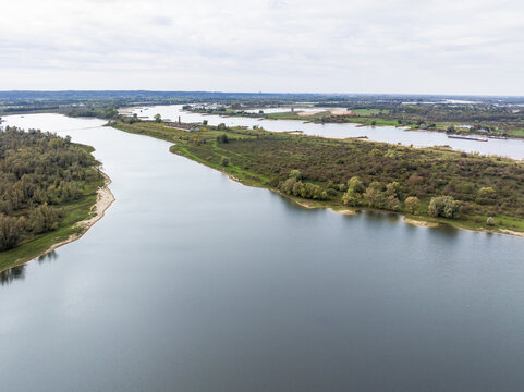 Aerial view of the Millingerwaard nature reserve featuring the winding river Waal and side channel, lush wetlands, and green vegetation in Kekerdom, Gelderland, Netherlands.