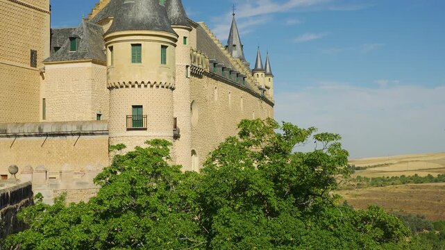 Side view of the Alcazar of Segovia with slate roof turrets and patterned stone walls