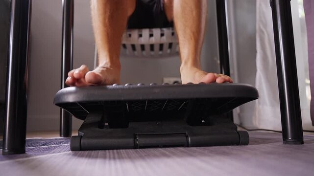 Bare Feet Adjust an Ergonomic Footrest Under a Desk, Supporting Comfortable Seated Posture and Workplace Wellbeing