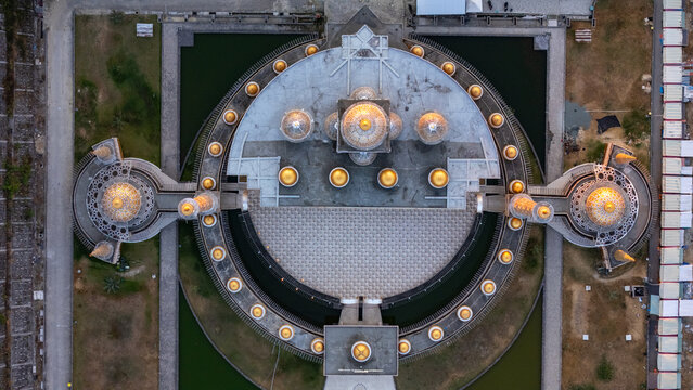 Aerial view of the grand mosque with its prominent golden domes and symmetrical circular architecture surrounded by water features in Bojonegoro, East Java, Indonesia.