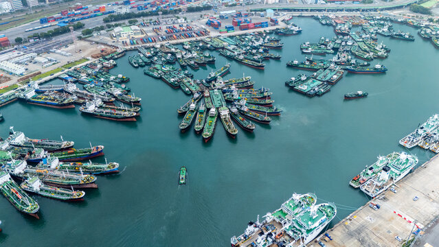 Aerial view of Busan Port featuring numerous cargo ships and tankers docked in the harbor with shipping containers visible on the pier in Busan, Busan, South Korea.