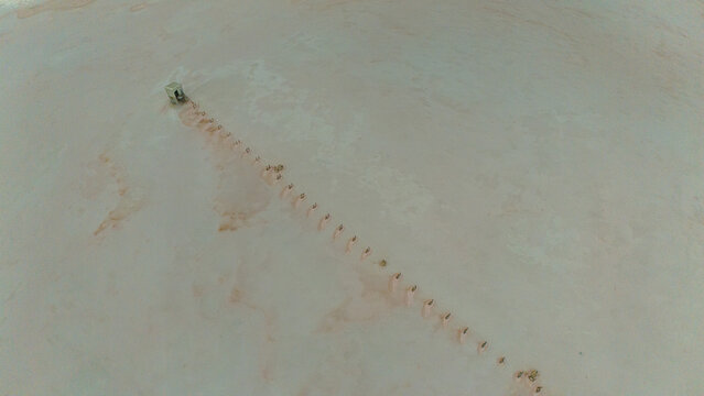 Aerial view of Koyuncu Tuz Isletmesi salt lake with a line of salt extraction structures and a small building in Sereflikochisar, Ankara, Turkiye.