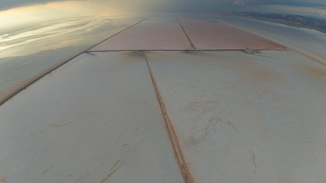 Aerial view of the Koyuncu Salt Works at Tuz Golu featuring geometric salt pans with pinkish water and vast white salt flats in Sereflikochisar, Ankara, Turkiye.