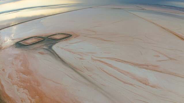 Aerial view of the Koyuncu Salt Works at Tuz Golu, featuring vast salt flats, geometric evaporation ponds, and textured mineral deposits in Sereflikochisar, Ankara, Turkey.