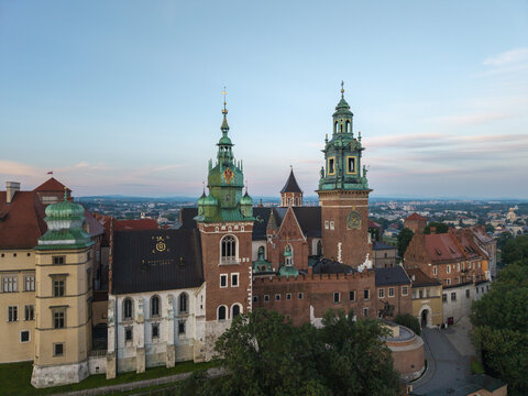 Aerial view of Wawel Royal Castle with its distinctive green-domed towers and historic red brick architecture surrounded by lush greenery in Krakow, Malopolskie, Poland.