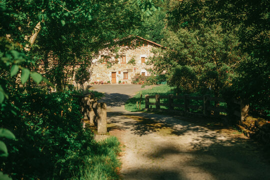 Traditional Basque stone house caserio viewed over wooden bridge and dirt path in Spain.