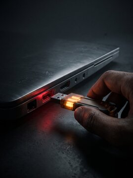 Glowing USB drive with red warning light inserted into laptop representing hardware security threat