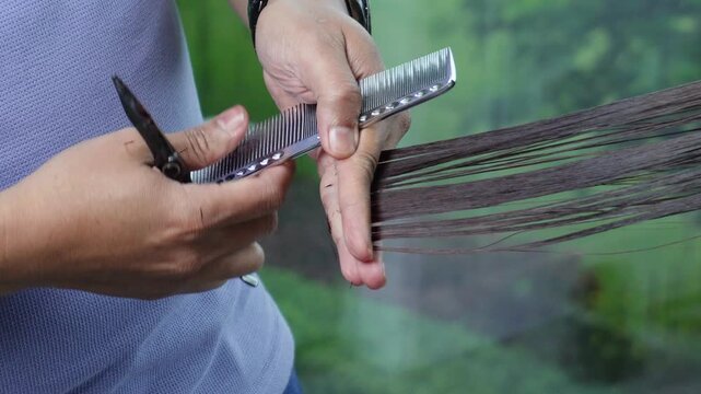 Hair stylist trimming long hair ends after professional rebonding treatment. Closeup shot.