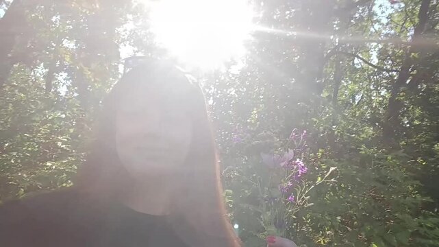 Woman with wildflowers while walking in the forest